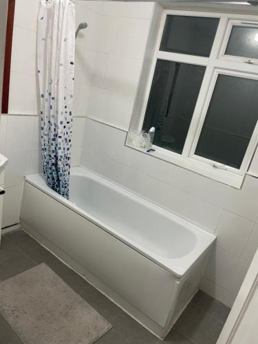 a white bath tub in a bathroom with a window at Welcome to your new home. in Redbridge