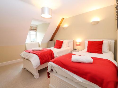 two beds in a room with red and white at Saffron, Blythview in Blythburgh