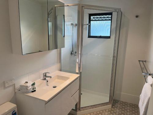 a white bathroom with a shower and a sink at Noosa Lakes Resort in Noosaville