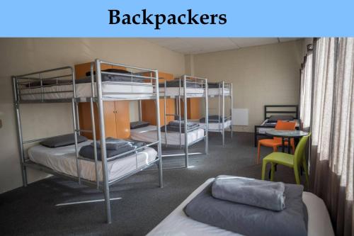 a room with three bunk beds and a table at Strahan Retreat Holiday Park in Strahan