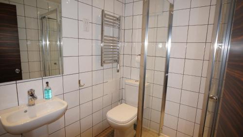 a white tiled bathroom with a toilet and a sink at Crestfield Hotel in London