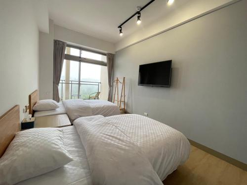 a bedroom with two beds and a flat screen tv at 畔山民宿 in Fenchihu
