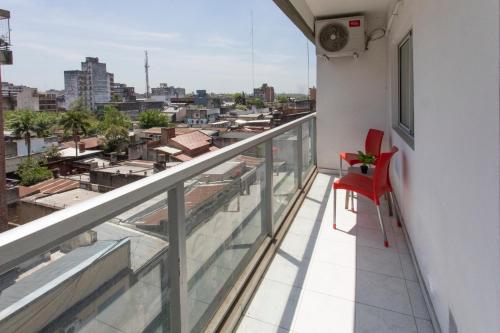 una silla roja sentada en un balcón con vistas a la ciudad en Local Experience in SMDT - cerca de Casa Historica en San Miguel de Tucumán