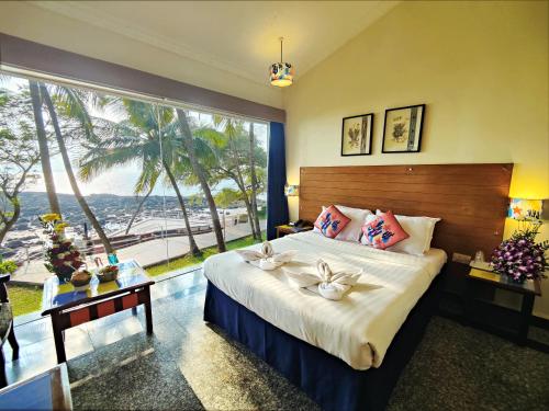 a bedroom with a large bed and a large window at Bambolim Beach Resort in Bambolim