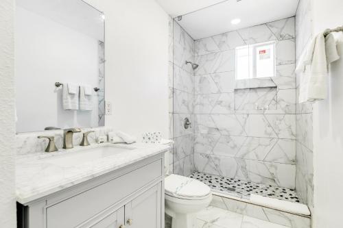 a white bathroom with a toilet and a shower at Bellaire West Retreat in Houston