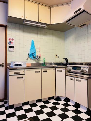 a kitchen with white cabinets and a checkered floor at アニメーションの起源地にある大泉学園ヴィラ in Katayama