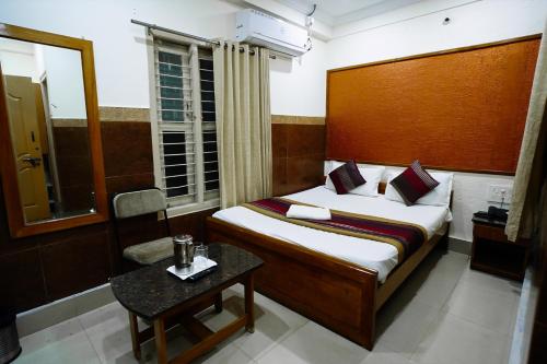 a bedroom with a bed and a chair and a table at HOTEL PRAKAASH RESIDENCY in Mysore