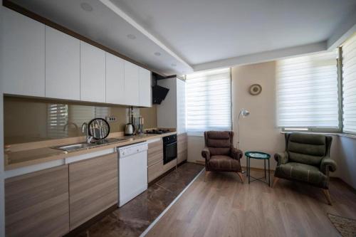 a kitchen with white cabinets and two chairs at ABC Apart Hotel in Antalya