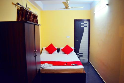 a small bedroom with a bed with red pillows at Skyline Lodge in Siliguri