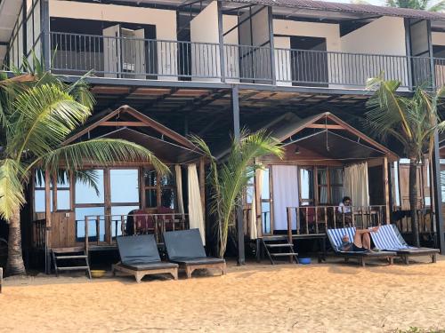 a hotel on the beach with chairs and palm trees at Madhu Huts Agonda in Agonda