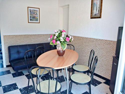 une table avec des chaises et un vase de fleurs dessus dans l'établissement Appartement T2 ensoleillé à 2 pas de la plage avec terrasse, parking et wifi options - FR-1-387-123, à Marseillan