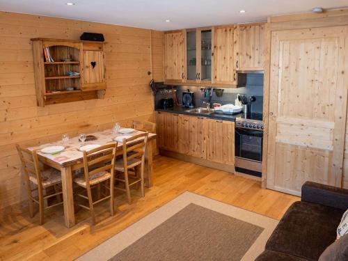 une cuisine avec des armoires en bois et une table avec des chaises dans l'établissement Val Thorens - Bel Appartement 4 pers, Balcon Sud, TV, Bluetooth, Cuisine Équipée, Local à Skis - FR-1-637-32, à Val Thorens