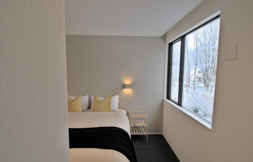 Myoko Apartments في Akakura: غرفة نوم بسرير ونافذة