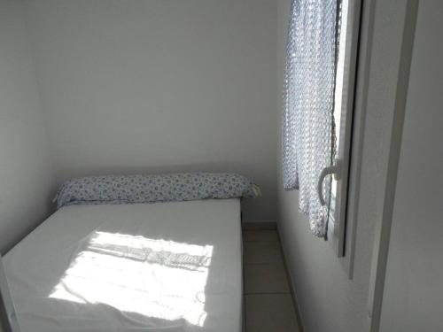 un petit lit dans une chambre avec une fenêtre dans l'établissement Appartement 2 pièces, terrasse, parking privé, proche plage et centre, Grau-du-Roi - FR-1-250-174, au Grau-du-Roi