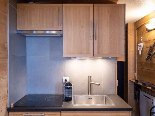 une cuisine avec un évier et des armoires en bois dans l'établissement Appartement rénové 22 m² - Val Thorens - 3 pers - Skis aux pieds - Confort & WiFi - FR-1-637-42, à Val Thorens