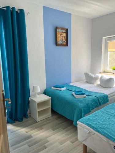 a bedroom with two beds and a blue wall at Apartamenty Jeanette in Rowy