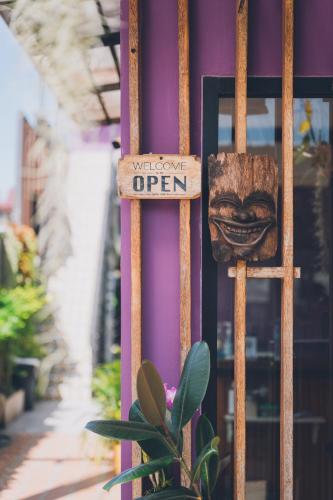 a sign on the side of a purple building with a plant at The Villager Fishermans Village in Bophut