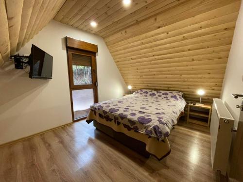 sypialnia z łóżkiem w pokoju z drewnianymi ścianami w obiekcie Vila Vlajić 2020 w mieście Gornje Pale