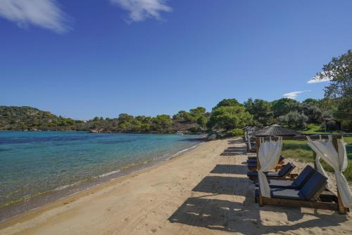 a row of chairs and umbrellas on a beach at Serenity Estate in Ormos Panagias