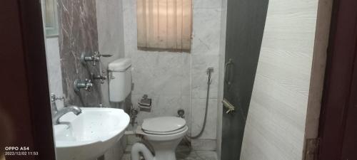 a bathroom with a white toilet and a sink at Skyline Lodge in Siliguri