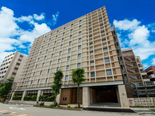 un gran edificio con árboles delante de él en Hotel Torifito Naha Asahibashi, en Naha