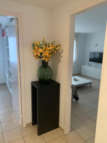 eine Vase mit Blumen auf einem schwarzen Stand in einem Wohnzimmer in der Unterkunft Pis Cala Tere in Cadaqués