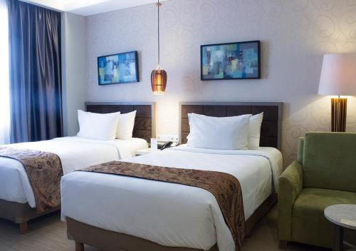 a hotel room with two beds and a chair at BW Kemayoran Hotel & Convention Powered by Archipelago in Jakarta