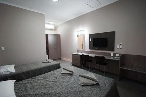 Habitación de hotel con 2 camas y TV de pantalla plana. en Bluestone Motor Inn, en Tennant Creek