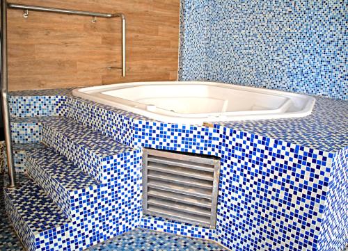 La salle de bains est pourvue de carrelage bleu et blanc ainsi que d'une baignoire. dans l'établissement 56 Oceanic Holiday Apartment, à Durban
