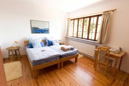 a bedroom with a bed and a desk and a window at Jagdhaus am Bach in Losheim
