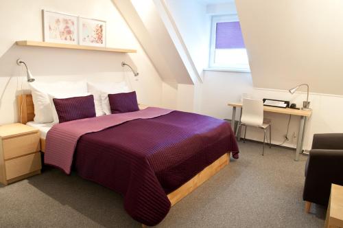 a bedroom with a purple bed with a desk and a window at Hotel Berger in Kamenice nad Lipou