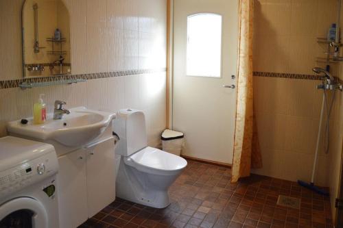 a bathroom with a toilet and a sink and a washing machine at Ekokatti Cottages in Vuokatti