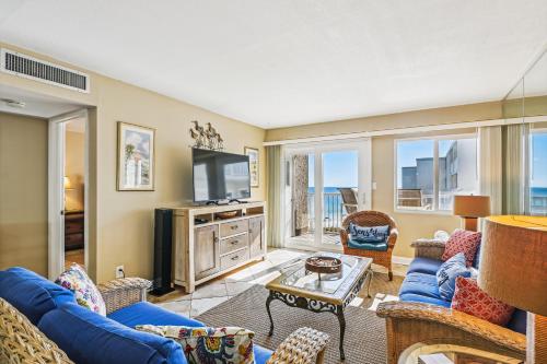 sala de estar con sofás azules y TV en Holiday Surf & Racquet 614 Condo en Destin