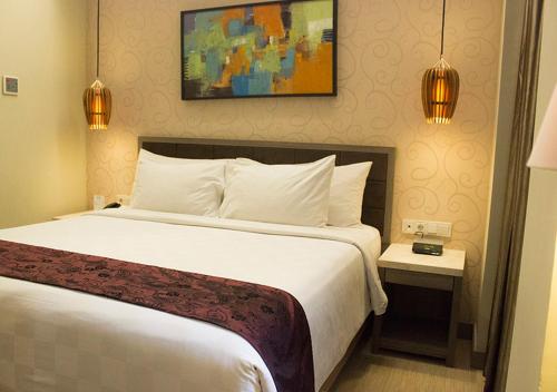 a hotel room with a large bed with white sheets at BW Kemayoran Hotel & Convention Powered by Archipelago in Jakarta