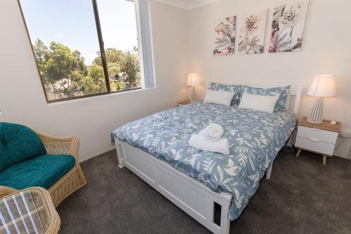 um quarto com uma cama, uma cadeira e 2 janelas em Sunrise @ the Point - Lovely 2 bdr unit with Pool em Soldiers Point