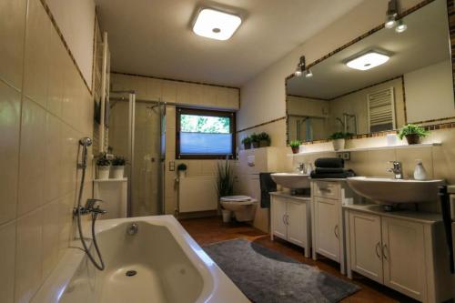 La salle de bains est pourvue de 2 lavabos, d'une baignoire et d'un lavabo. dans l'établissement Ferienwohnung Schöne Aussicht am Rothaarsteig, à Bad Laasphe