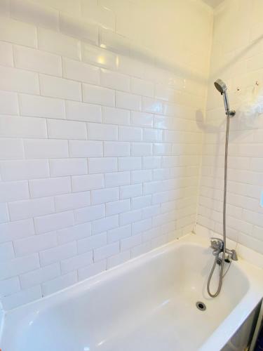 a white bath tub with a shower in a bathroom at Cozy & Quiet Two Bedroom Apartment in Chingford
