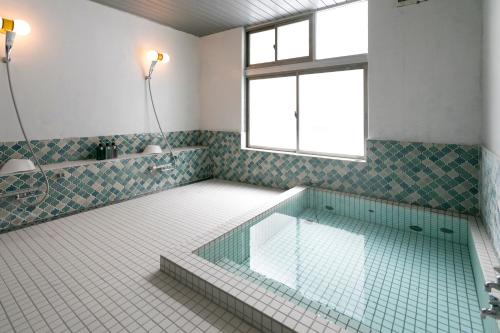 a bathroom with a glass tub with a window at Square 8 HAKUBA RETREAT by UNPLAN in Hakuba