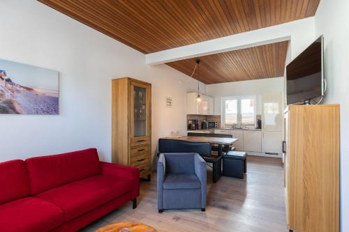 a living room with a red couch and a kitchen at Haus Relax, Whg 3 in Duhnen