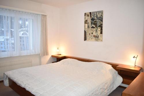 a bedroom with a white bed and two lamps on tables at Allod (369 St) Whg. Nr. 402 in Lenzerheide