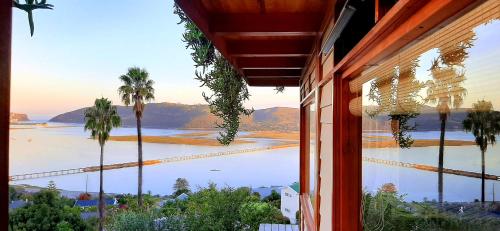 una finestra con vista sull'acqua e sulle palme di Paradise Private Zen Studios a Knysna