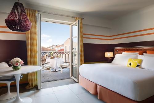 a bedroom with a bed and a balcony with a table at Hôtel de Paris Saint-Tropez in Saint-Tropez