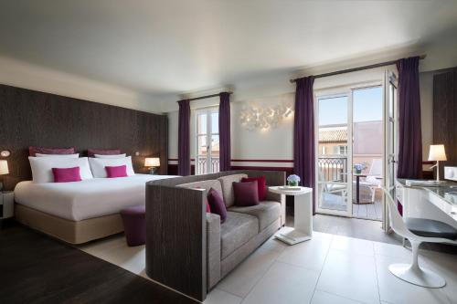 a hotel room with a bed and a couch at Hôtel de Paris Saint-Tropez in Saint-Tropez