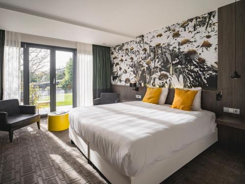 - une chambre avec un grand lit et une grande peinture murale dans l'établissement Van der Valk Hotel Heerlen, à Heerlen
