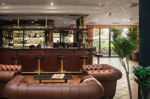 a bar with brown leather furniture and a bar counter at Hotel Roma Prague in Prague