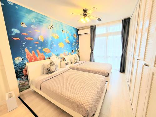 a bedroom with two beds and an aquarium wall at "沖縄の美ら海をイメージしたコンセプトルーム, 100インチスクリーン&,プロジェクターで映画三昧!, ゆったり64平米2LDK" Villa Blu Okinawa Chatan 3-3 ヴィラブルー沖縄北谷3-3 in Chatan
