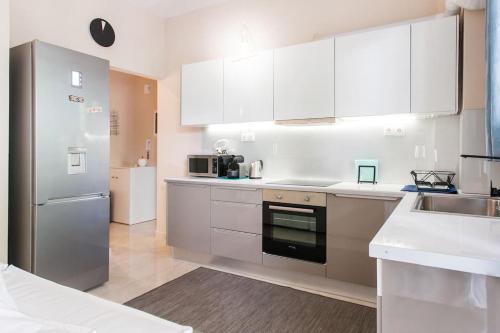 a kitchen with white cabinets and a stainless steel refrigerator at Lux Beach Apartment in Vari