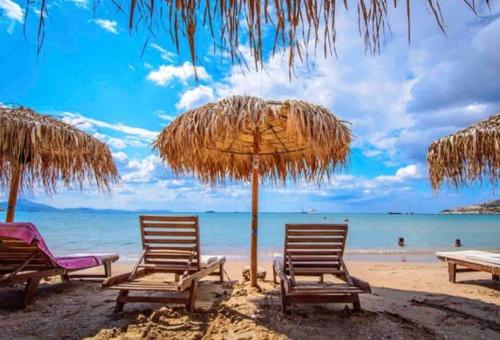 a group of chairs and an umbrella on a beach at Lux Beach Apartment in Vari