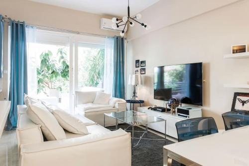 a living room with white furniture and a flat screen tv at Lux Beach Apartment in Vari