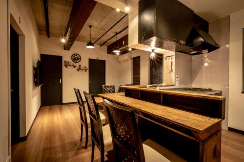 uma cozinha com um balcão de madeira com cadeiras e um lavatório em LifeHouse IPPO em Otaru